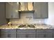 Modern kitchen featuring gray cabinets, a stainless steel range hood, and granite countertops at 7047 Noble Flair Ct, Las Vegas, NV 89131