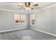 Bright bedroom featuring plush carpet, a ceiling fan, and multiple windows with neighborhood views at 3531 W Arby Ave, Las Vegas, NV 89118