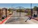 Community gate with black metal fencing, mature landscaping, and visible neighboring houses in the area at 6724 Reggie Cir, Las Vegas, NV 89107