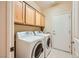 Convenient laundry room with wooden cabinets and a side-by-side washer and dryer at 7804 Island Rail Dr, North Las Vegas, NV 89084