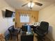 Well-lit office with dark desk, ceiling fan and mounted TV, ideal for working from home at 2710 Mustang Pass St, Laughlin, NV 89029