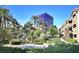 Condo complex with landscaped grounds, mature trees, and partial view of casino under clear blue sky at 4200 S Valley View Blvd # 3030, Las Vegas, NV 89103