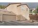 Attached garage with a tan door and exterior lighting at 9790 Overlook Ridge Ave, Las Vegas, NV 89148