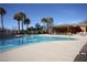 Resort-style pool featuring lounge chairs, palm trees, and a beautiful clubhouse in a tranquil community setting at 565 Fairways Dr, Mesquite, NV 89027