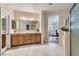 This bathroom boasts dual sinks, wood cabinets, tile floors, and an open doorway to the primary bedroom at 3605 Sapphire Sea Ct, North Las Vegas, NV 89031