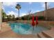 Stunning pool and spa with red umbrellas and a waterfall feature at 12253 Bluebird Canyon Pl, Las Vegas, NV 89138