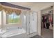 Bright bathroom features a glass enclosed shower, tub, and a large walk-in closet at 716 Solitude Point Ave, Henderson, NV 89012