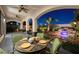Inviting covered patio with dining area overlooking the lush backyard with a tranquil waterfall feature at twilight at 2781 Josephine Dr, Henderson, NV 89044