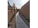 An outside view shows a long sidewalk between houses, landscaping rock and several young trees at 10205 Starlit Canyon Ct, Las Vegas, NV 89141