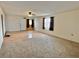 Bright living room with a ceiling fan, front door, neutral carpeting and two windows at 2510 N Woodchips Rd, Pahrump, NV 89060