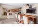 Inviting bar area with wooden bar, seating, carpeted floor, and view into kitchen at 8737 Autumn Valley Ave, Las Vegas, NV 89129