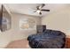 Spacious bedroom with large bed, carpeted floor, ceiling fan, and view from arched window at 8737 Autumn Valley Ave, Las Vegas, NV 89129