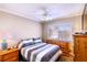 Cozy bedroom featuring a ceiling fan, wooden dresser and natural light from the window at 8737 Autumn Valley Ave, Las Vegas, NV 89129