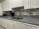 Close-up of kitchen with white cabinets, gray countertops, stainless sink, and modern backsplash at 1812 Ryan Ave, Las Vegas, NV 89101
