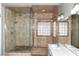 Well-lit main bathroom with a glass enclosed walk-in shower, double sinks, and tile walls at 427 Norridgewock St, Henderson, NV 89074