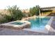 Backyard pool and spa featuring brick accents, rock waterfalls, and green landscaping at 427 Norridgewock St, Henderson, NV 89074