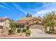 Two-story house with tan exterior, tile roof, and landscaped front yard at 1590 Sabatini Dr, Henderson, NV 89052