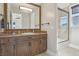 Bathroom featuring a framed mirror, granite countertop, custom cabinetry, and a glass-enclosed shower at 1529 Villa Rica Dr, Henderson, NV 89052