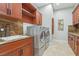 This laundry room offers wooden cabinets, granite countertops, stainless steel washer and dryer, and tile flooring at 1529 Villa Rica Dr, Henderson, NV 89052