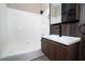 Bathroom featuring tub with white tile surround, modern vanity with dark wood-look accent wall at 2151 Hussium Hills St # 207, Las Vegas, NV 89108