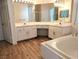 Bathroom with double sinks, vanity, soaking tub, and wood-look flooring at 9728 Echo Hills Dr, Las Vegas, NV 89134