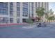 View of the apartment building entrance with palm trees and parking for bikes and scooters at 3930 University Center Dr # 1003, Las Vegas, NV 89119