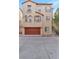 Exterior view of a two-story home with a two-car garage and desert landscaping, complete with a red garage door at 6485 Arrow Cottage Ct, Las Vegas, NV 89130