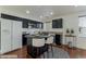 Well-lit kitchen features modern black cabinets and an island with white bar stools at 6485 Arrow Cottage Ct, Las Vegas, NV 89130