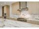 Close-up of kitchen island and range with stainless steel hood and marble backsplash and countertops at 19 Rue Grimaldi Way, Henderson, NV 89011