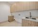 Bright laundry room features custom cabinetry and a stone countertop with stainless steel sink and modern faucet at 19 Rue Grimaldi Way, Henderson, NV 89011