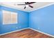Bright empty blue bedroom featuring wood floors, a ceiling fan, and natural light from a window at 1053 Plentywood Pl, Henderson, NV 89002