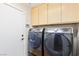 This laundry room features a front loading washer and dryer set, light colored cabinets, and wood flooring at 1053 Plentywood Pl, Henderson, NV 89002