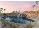 Serene pond with waterfall feature and palm trees at sunset at 16 Via Stefano, Henderson, NV 89011