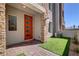 Brick paved patio with artificial turf and modern orange door at 600 N Carriage Hill Dr # 1113, Las Vegas, NV 89138