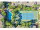 Aerial view of a blue tennis court next to a pool surrounded by lush tropical greenery and buildings at 7139 S Durango Dr # 218, Las Vegas, NV 89113