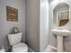 Well-lit half bathroom featuring a pedestal sink, a toilet, and modern decor at 6482 Twin Harbors Ct, Las Vegas, NV 89141