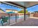 Covered patio view of a fenced, in-ground pool and brick surround with desert landscaping and outdoor furniture at 6482 Twin Harbors Ct, Las Vegas, NV 89141