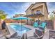 Beautiful in-ground swimming pool surrounded by stone with chairs and sun umbrella with a balcony on the home at 6482 Twin Harbors Ct, Las Vegas, NV 89141