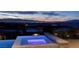 Relax in this home's modern hot tub with stunning views of the city skyline at dusk at 673 Falcon Cliff Ct, Henderson, NV 89012