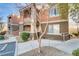 Exterior view of the building showcasing stucco facade, manicured landscaping, and convenient sidewalk access to units at 7701 Himalayas Ave # 104, Las Vegas, NV 89128