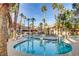 Community pool with mature palms, lounge chairs, and meticulously landscaped grounds at 7701 Himalayas Ave # 104, Las Vegas, NV 89128