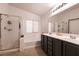 Well-lit bathroom with a dual sink vanity, a tub, and a glass-enclosed shower stall at 7936 Dexter Falls St, Las Vegas, NV 89149