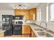 Functional kitchen with wood cabinets, black appliances, and dual basin sink at 260 E Desert Rose Dr, Henderson, NV 89015