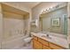 Well-lit bathroom with a bathtub, shower, white tile, and a classic wooden vanity at 7151 S Durango Dr # 214, Las Vegas, NV 89113