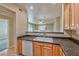 Galley kitchen with tile countertops, wood cabinets, and a view into the living room at 7151 S Durango Dr # 214, Las Vegas, NV 89113