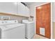 Bright laundry room with washer, dryer, cabinets, and access door for pets at 1550 Desertaire Way, Las Vegas, NV 89110