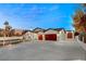 Stunning exterior view of the home, highlighting its red garage doors, driveway, and well-lit landscaping at 1725 Bannie Ave, Las Vegas, NV 89102