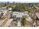 Stunning aerial view of a modern, flat-roofed home with circular driveway, landscaping, and Las Vegas skyline in the distance at 2401 Driftwood Dr, Las Vegas, NV 89107