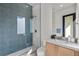 Modern bathroom with blue tile shower and a glass partition, plus a wood vanity at 2401 Driftwood Dr, Las Vegas, NV 89107