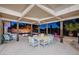 Covered patio featuring dining table with view of the pool and fire feature at dusk at 2240 Mohigan Way, Las Vegas, NV 89169